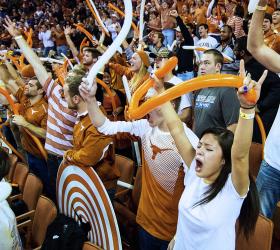 Longhorns fans cheering for the team in a packed stadium.