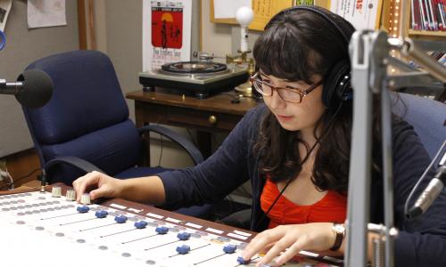 Student adjusting sound board in KVRX studio.
