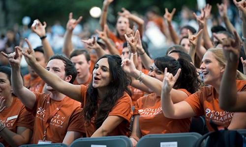 Students at Gone to Texas wear orange shirts while giving the hook 'em sign.