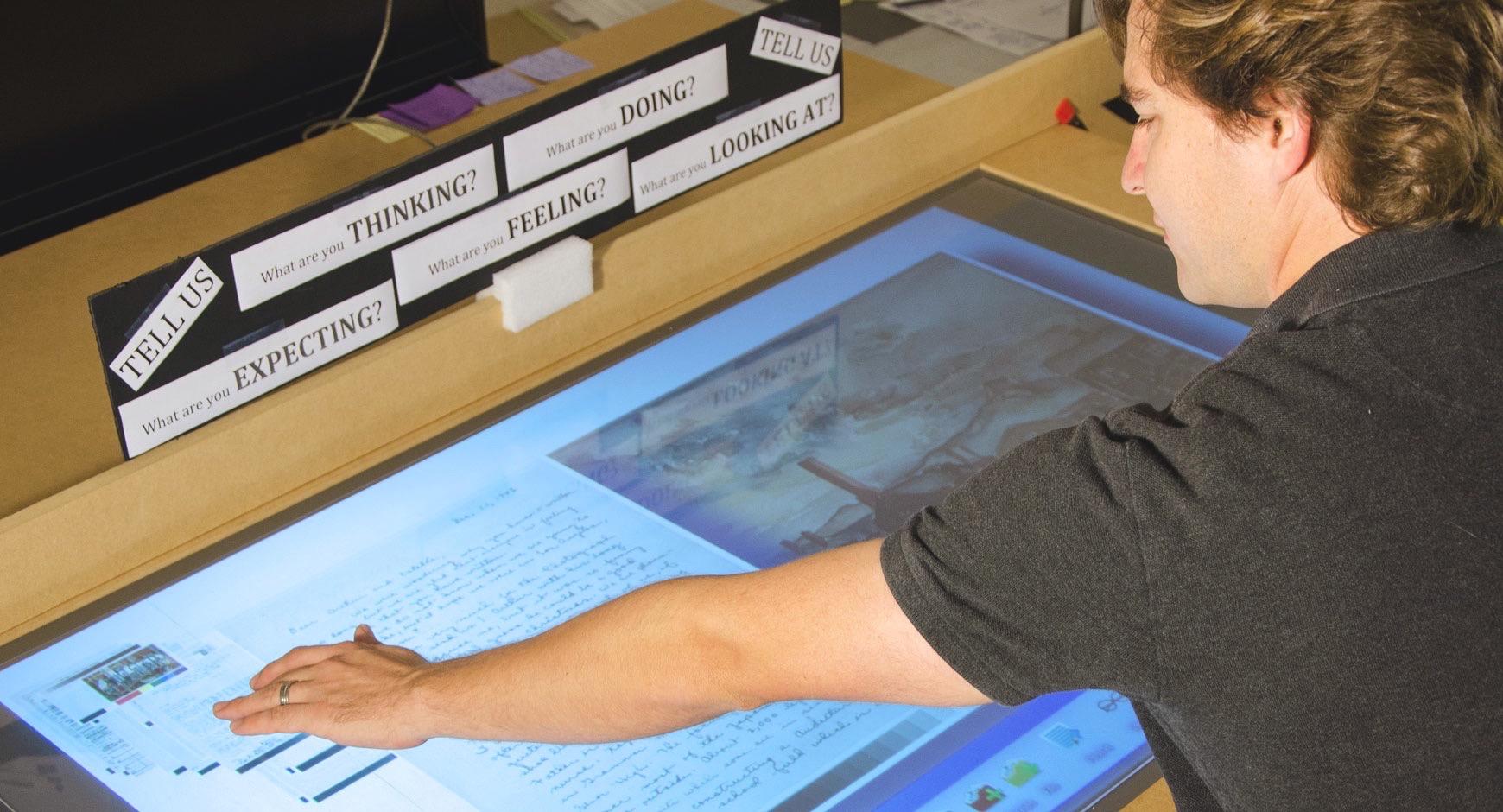 Student examines archived work on large touch screen display.