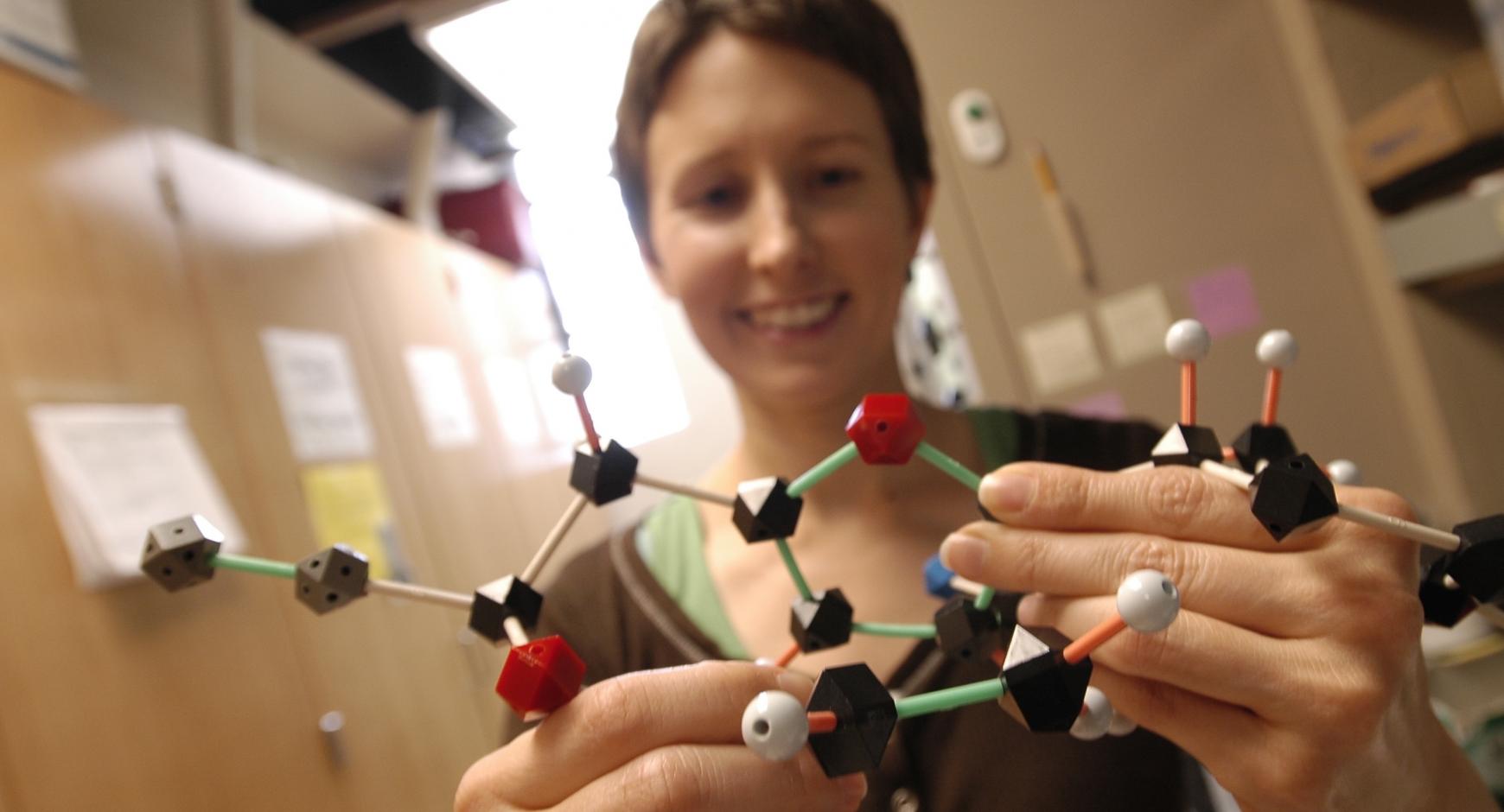 Student in lab holding a chemistry model.