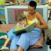 College student reading book with young child.