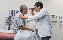Dell Med student checking a patient's eyes