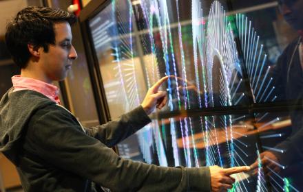 An undergraduate researcher using a large touchscreen in the TACC Vislab
