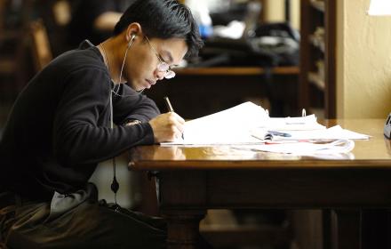 Student studying lecture notes in library.