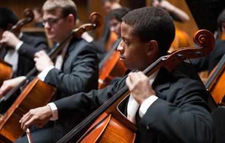 Student playing instrument in orchestra.