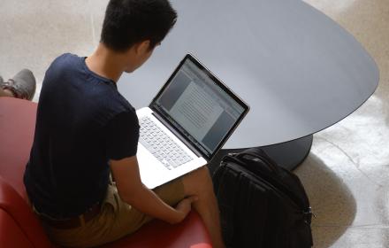 Student writing a paper on laptop.